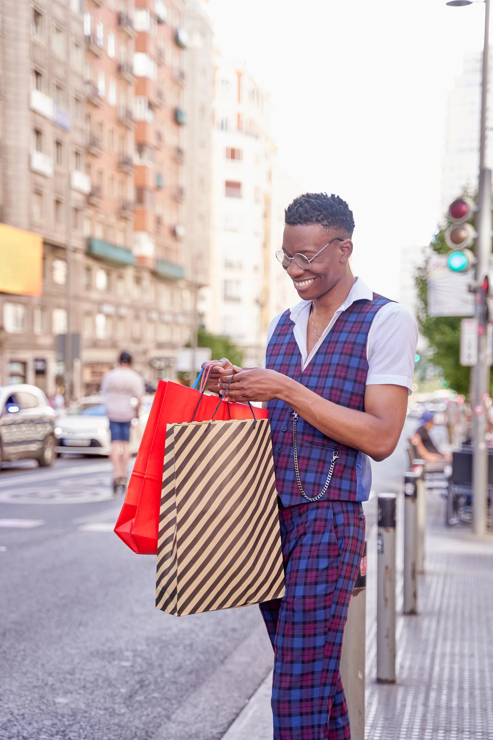 Man holding shopping bags while checking his phone on a city street