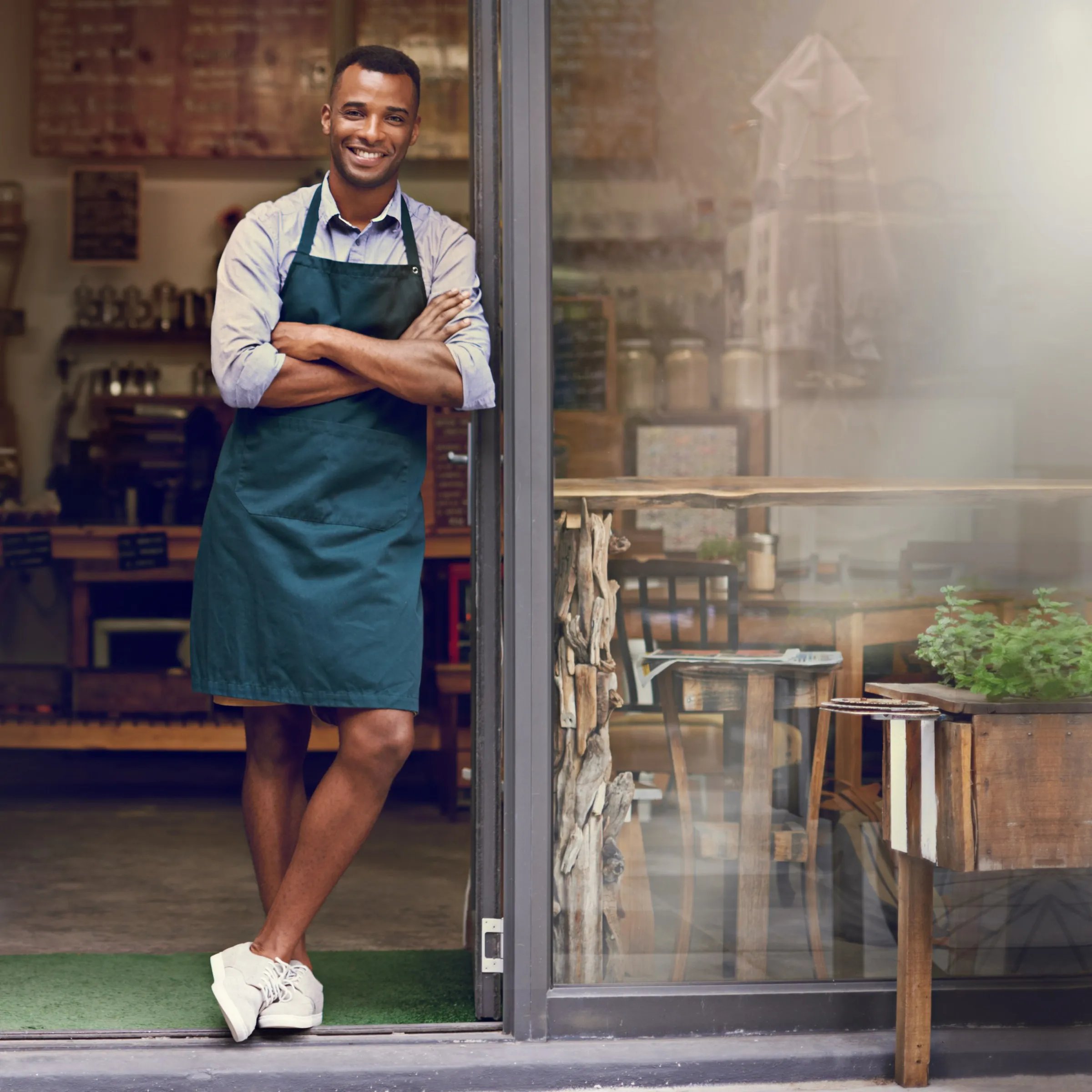 Smiling café owner standing at the front door of his shop